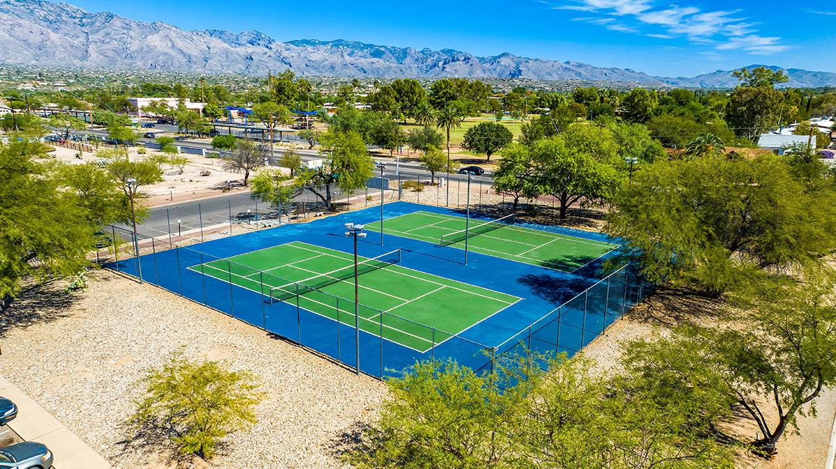 Two tennis courts surrounded by landscaped grounds.