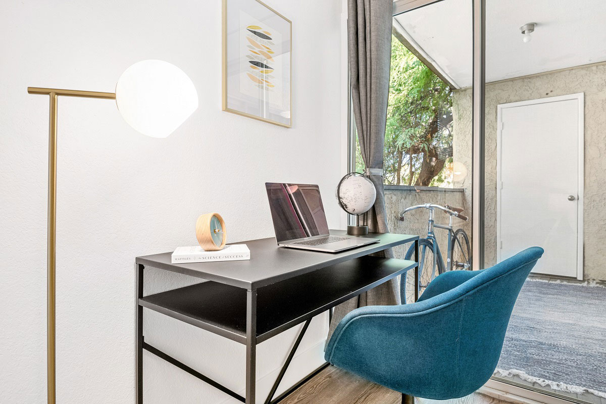 Desk beside a large window in a furnished apartment.